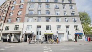 Un edificio de varios pisos con una tienda en la planta baja y un servicio de alquiler de bicicletas.