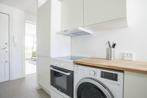 A modern kitchen with a built-in oven, a washing machine, and a wooden countertop. - Great 1-bed in Christians Harbour (Copenhagen)