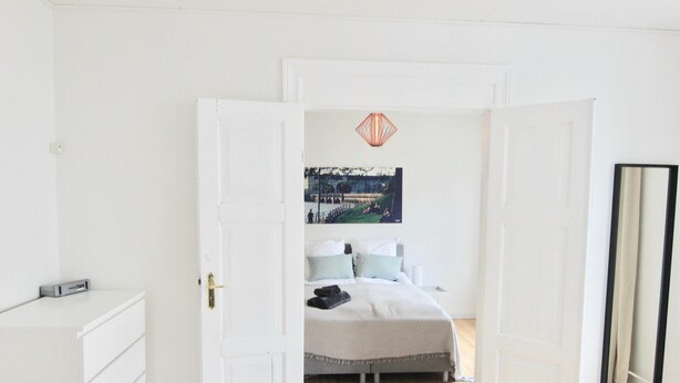 A bedroom with a bed, a dresser, a mirror, and a painting on the wall. - 2-bed Apartment in one of Rhus Best Locations (Aarhus)