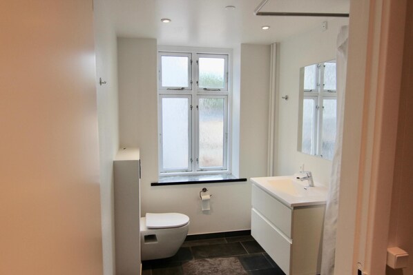 A small, modern bathroom with a toilet, sink, and window. - 2-bed Apartment in one of Rhus Best Locations (Aarhus)