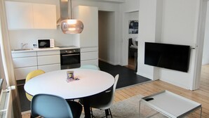 A modern kitchen with white cabinets, a microwave, and a dining area with a round table and chairs. - 2-bed Apartment in one of Rhus Best Locations (Aarhus)