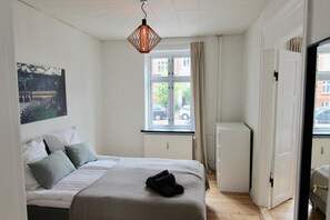 A bedroom with a bed, a window, a radiator, and a door. - 2-bed Apartment in one of Rhus Best Locations (Aarhus)