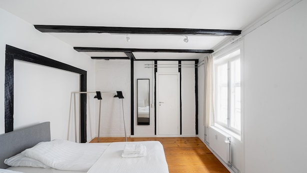 Ein modernes Schlafzimmer mit Bett, Kleiderschrank, Spiegel und Fenster.