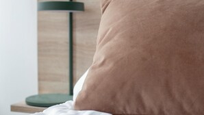 A bed with a brown pillow and white bedding, a green floor lamp, and a wooden headboard. - Beautiful 2-bed in top Copenhagen Location (Copenhagen)