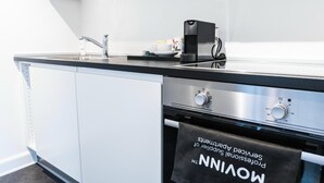 Una cocina moderna con encimera negra, electrodomésticos de acero inoxidable y una toalla colgada en la puerta del horno.