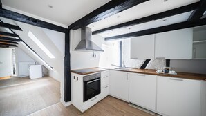 A modern kitchen with white cabinets, a wooden countertop, and a built-in oven. - Charming 2-bed Duplex in Great Location (Copenhagen)