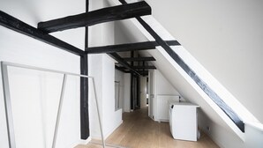 An attic room with exposed wooden beams, a radiator, and a white door. - Charming 2-bed Duplex in Great Location (Copenhagen)