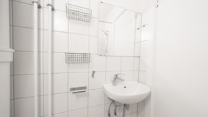 Un baño con lavamanos blanco, un espejo y una ducha.