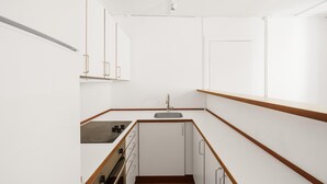 Una cocina compacta con armarios blancos, un lavamanos y una estufa.