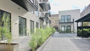 A modern building with balconies, large windows, and a paved walkway. - Stunning 2-bed w Large Balcony (Copenhagen)