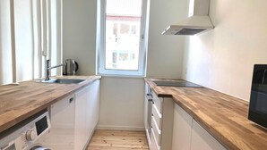 A compact kitchen with wooden countertops, a built-in washing machine, and a window providing natural light. - Great Refurbished 2-bed in Amager Island (Copenhagen)