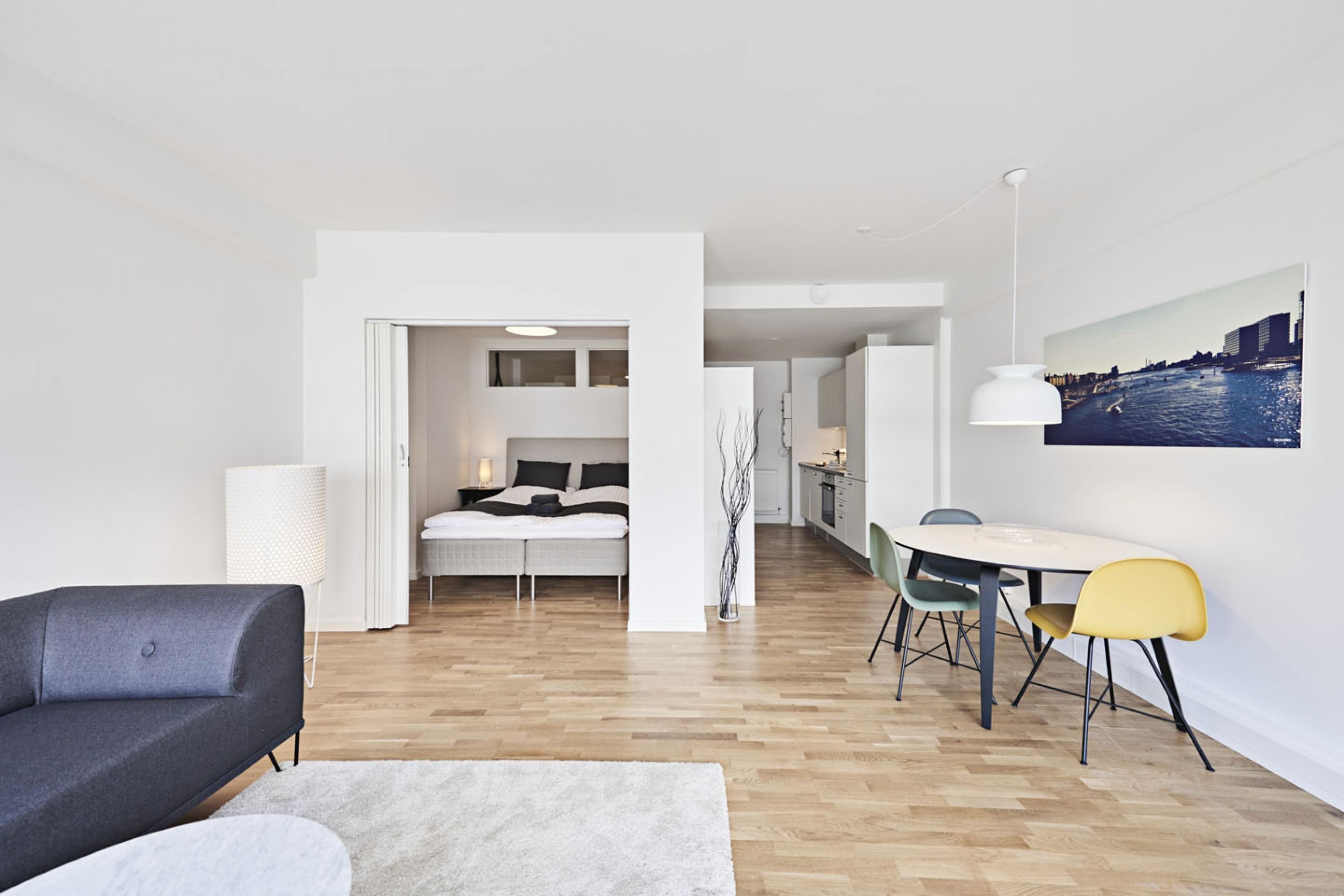 A modern apartment with a living area, a dining space, and a bedroom.