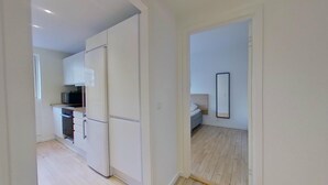Eine moderne Küche mit weißen Schränken, einem Kühlschrank und einer Mikrowelle.