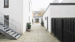 A narrow courtyard with a staircase, potted plants, and a black fence. - Fantastic 1-bed Apartment w Private Terrace (Aarhus)