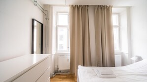 A bedroom with a bed, a dresser, a window with curtains, and a radiator. - Lovely 2-bedroom Apartment in the Heart of Copenhagen - 62 (Copenhagen)