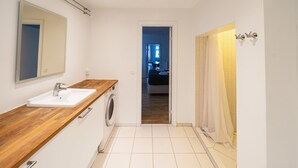 A modern bathroom with a wooden countertop, a sink, a washing machine, and a mirror. - Lovely 2-bedroom Apartment in the Heart of Copenhagen - 62 (Copenhagen)