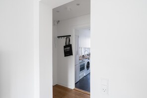 A hallway leading to a laundry area with a washing machine and dryer. - Refurbished 1-bed Close to Metro and Airport (Copenhagen)