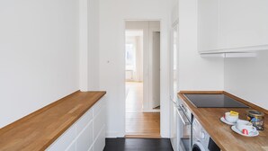Une cuisine étroite avec un plan de travail en bois, un lave-linge et un petit évier.