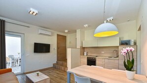 Een moderne keuken met een eethoek, een aan de muur bevestigde televisie en een trap naar een terras.
