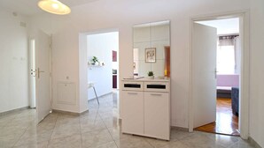 A hallway with a white cabinet, a hanging light fixture, and a door leading to another room.