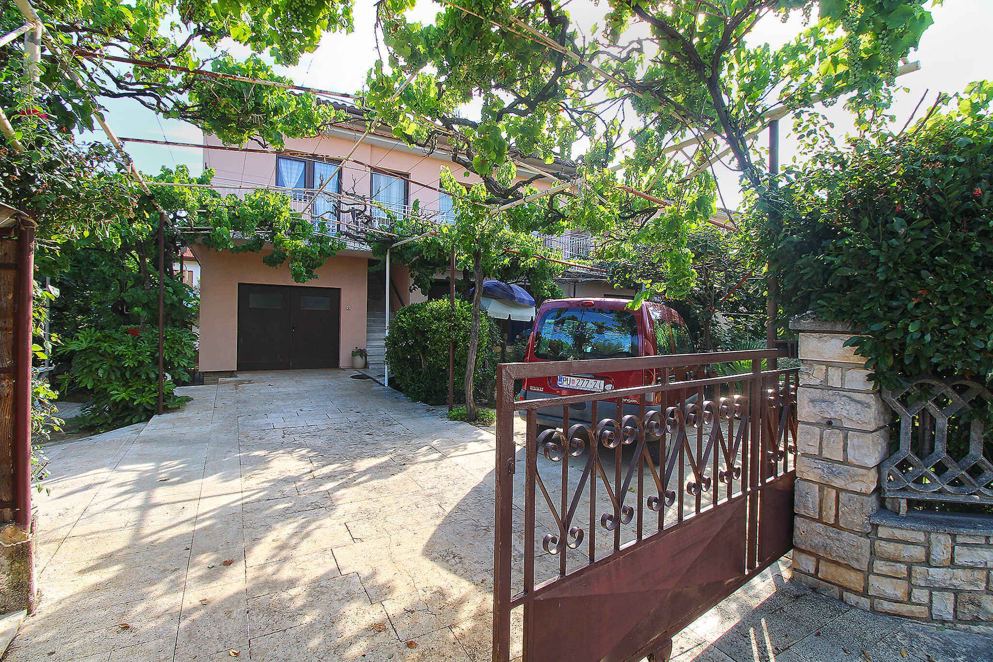A gated entrance to a residential property with a paved driveway leading to a garage.