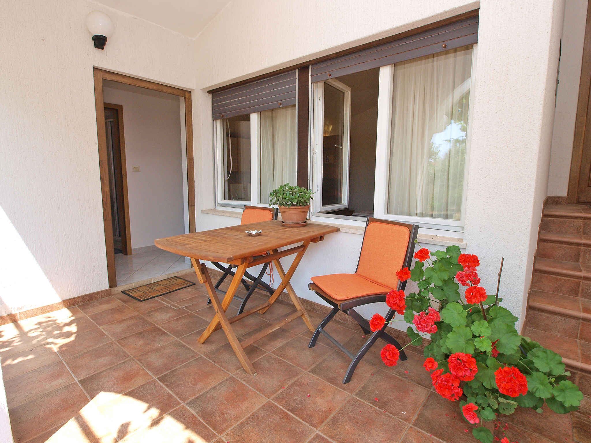 A patio with a wooden table and chairs, a potted plant, and a flower arrangement.