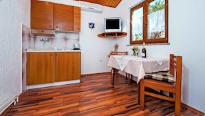 Een kleine keuken met houten kastjes, een ingebouwde televisie en een eethoek met een tafel en stoel.