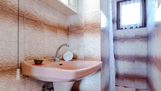 A bathroom with a sink, toilet, and a small window. - Holiday apartment with terrace and air conditioning (Rovinj)