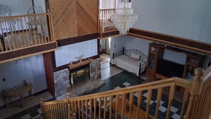 Un espacio habitable de varios niveles con una escalera de madera, chimenea, cama y televisor.