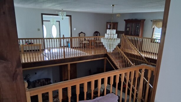 Habitación de varios niveles con escalera, candelabro y cama con almohadas.