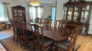 Un comedor con una mesa y sillas de madera, una araña y una alfombra estampada.