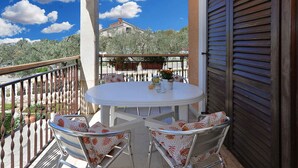 A balcony with a round table and chairs, overlooking a mountainous landscape. - Holiday apartment with garden and barbecue (Fažana)