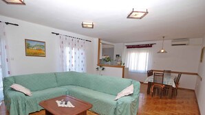 A living room with a green sofa, a wooden coffee table, and a dining area with a table and chairs. - Holiday apartment with air conditioning (Medulin)