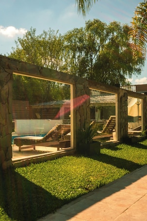 A stone-walled outdoor area with a pool, lounge chairs, and a staircase leading to a covered patio.