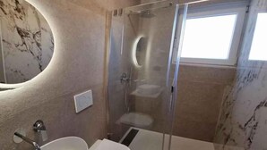 Un baño moderno con ducha de vidrio, lavamanos independiente y retrete.
