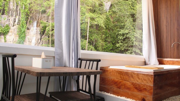 A room with a wooden table and chairs, a wooden cabinet, and a view of a forested cliff through a window. - MAYAD El Nido Inn (El Nido)