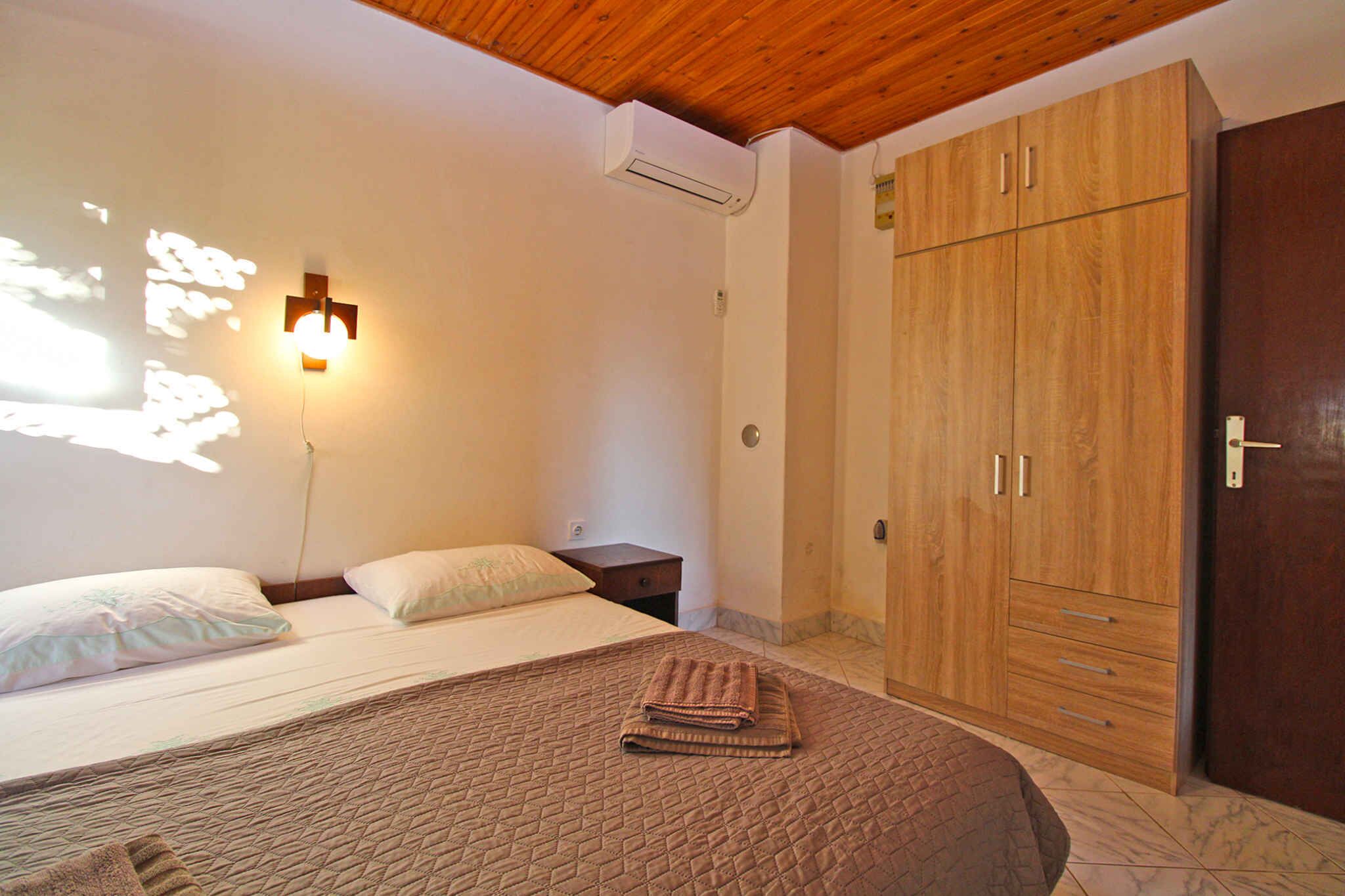 Quarto com cama, guarda-roupa, mesa de cabeceira e luminária na parede.