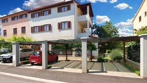 A multi-story residential building with a covered parking area and a garden. - Studio with garden and barbecue (Fažana)