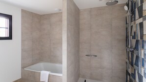 Ein modernes Badezimmer mit Badewanne, Dusche und Fliesen.