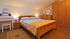 A bedroom with a wooden bed, bedside tables, a desk, a chair, and a wardrobe. - Holiday apartment with barbecue (Vinkuran)