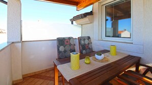 A wooden table with a woven tablecloth, two patterned cushions, a yellow cylindrical container, and a small potted plant. - Holiday apartment with barbecue (Vinkuran)