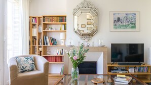 Un salon comprenant un canapé, une table basse, une cheminée, un téléviseur et des étagères à livres.