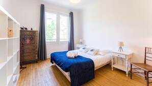 Une chambre à coucher avec un lit, une commode, une chaise et une fenêtre.