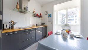 Une cuisine moderne avec des meubles gris, un plan de travail en bois et un coin repas avec une table dressée pour deux personnes.