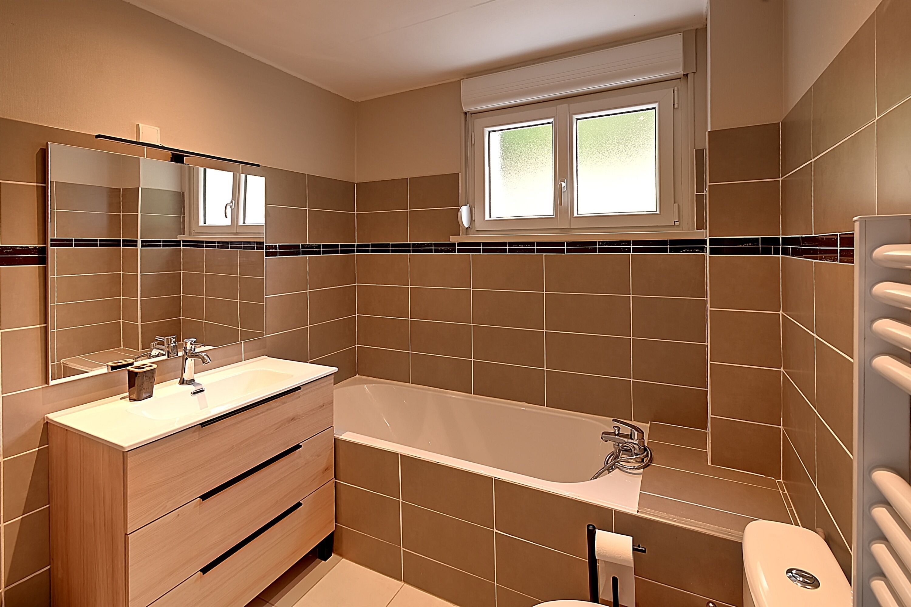 Ein modernes Badezimmer mit Badewanne, Waschtisch und einem großen Spiegel.