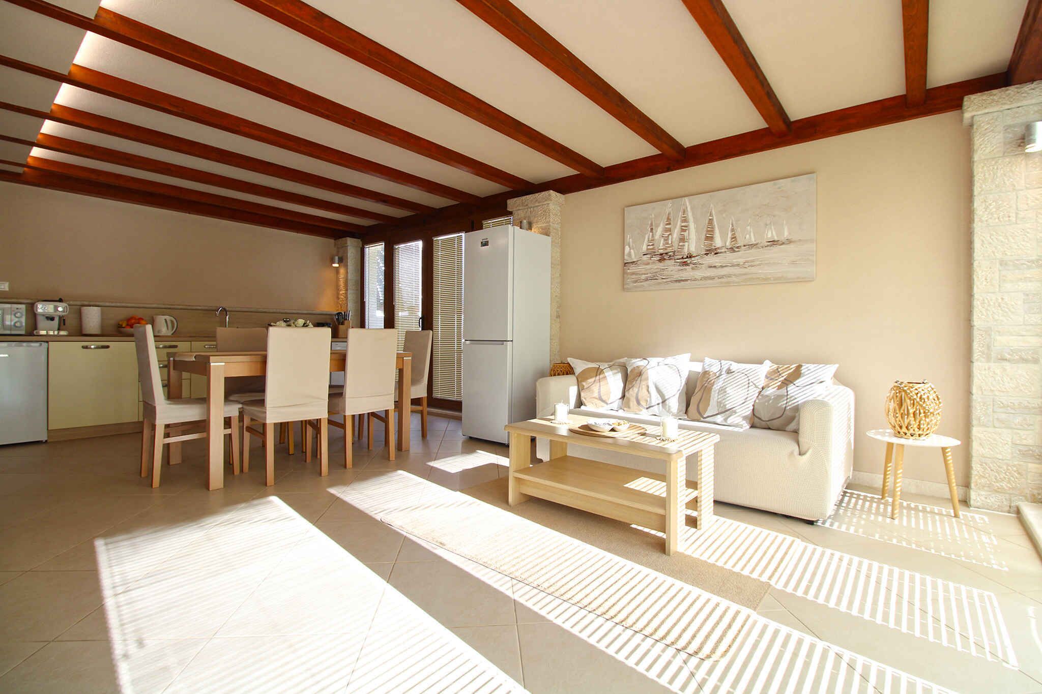 Uma sala de estar ampla com teto de madeira, um sofá, uma mesa de centro e uma área de jantar com cadeiras e mesa.