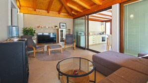 A living room with a television, seating, and a kitchen in the background. - Holiday apartment with barbecue (Vinkuran)