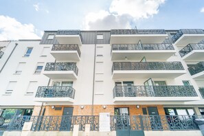 A multi-story residential building with balconies, a wooden facade, and a gated entrance. - Le Montfleury - Appt poche de Paris (Sarcelles)