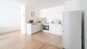 Una cuina moderna amb armaris blancs, forn integrat i nevera.