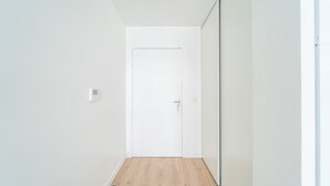 Un passadís estret amb terra de fusta, parets blanques i una porta blanca al final.